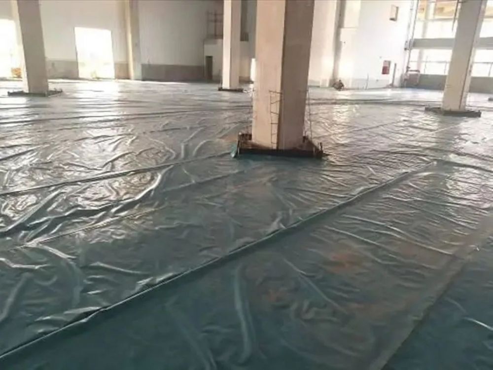 Laying heavy-duty plastic film moisture barrier for steel fiber reinforced concrete (SFRC) industrial flooring