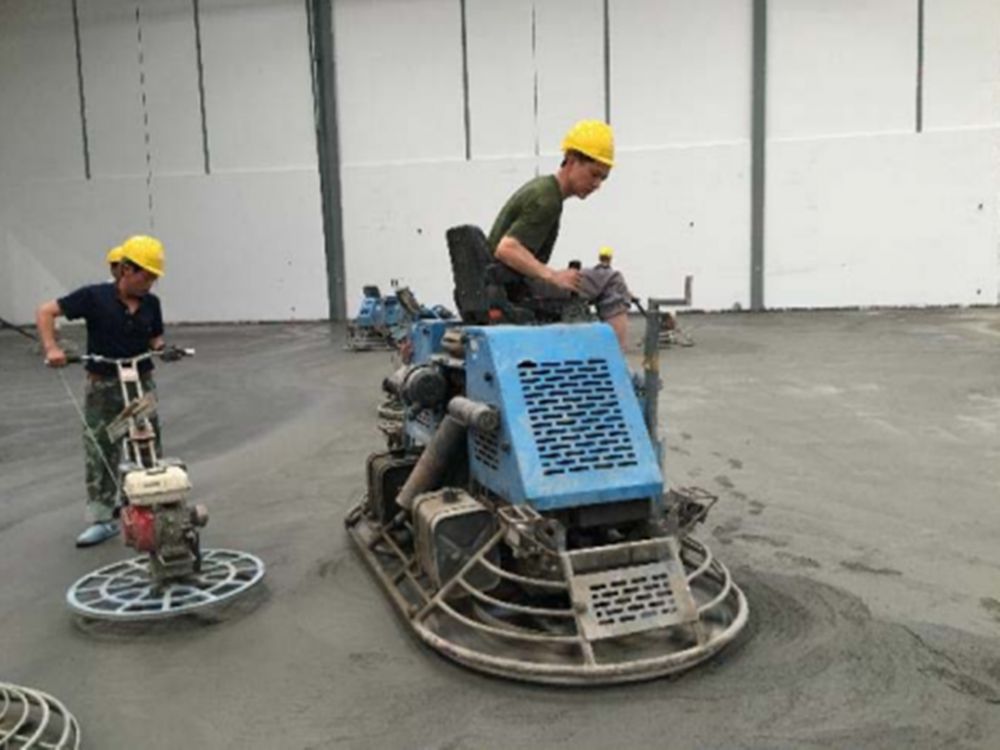 Using a power trowel to finish the surface of a steel fiber reinforced concrete industrial floor