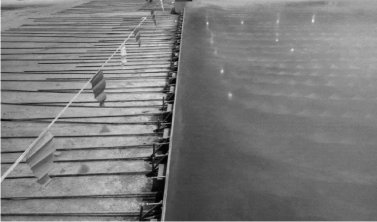 Concrete pouring and vibration process around armored joints to ensure dense consolidation and void-free industrial flooring.