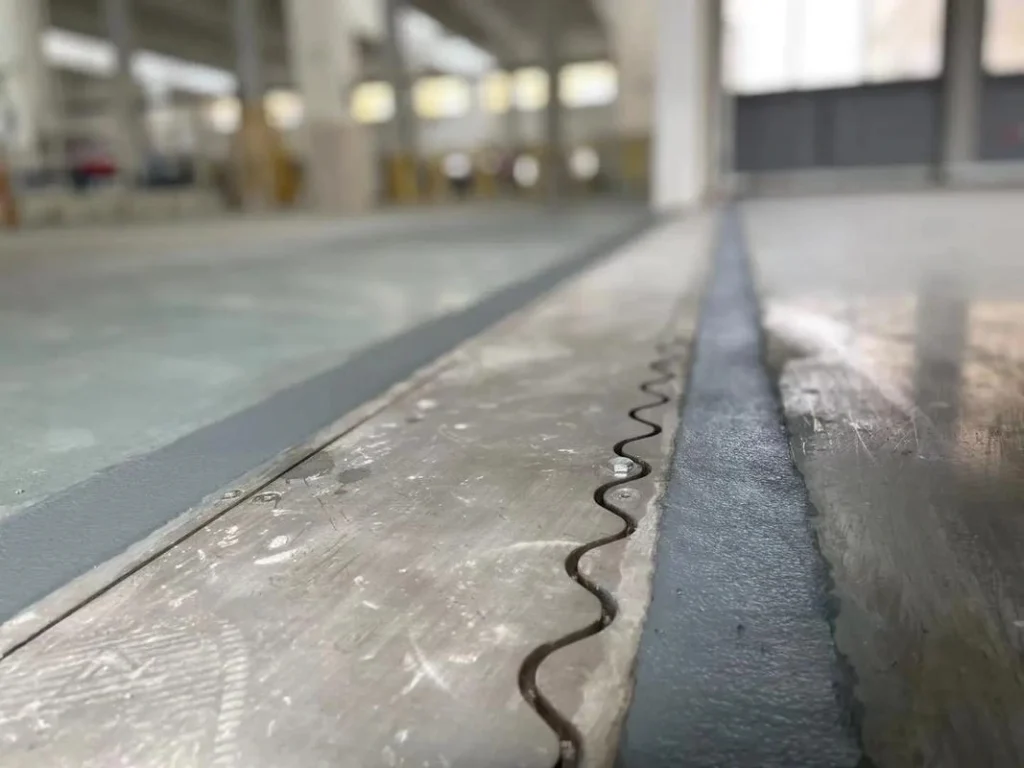 Finished heavy-duty concrete slab with wave-type armored joint for edge protection and expansion.